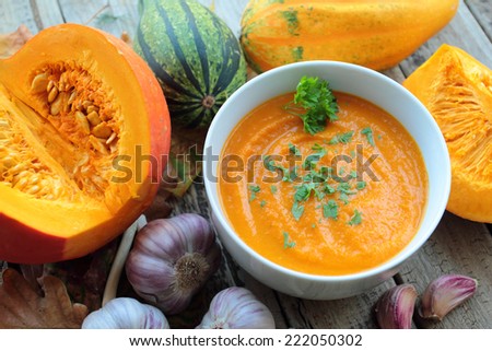 Pumpkin soup in a bowl with pumpkins and garlic