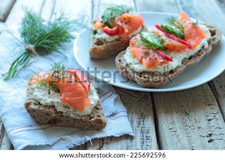 Plate with sandwiches with salmon on a wooden table boards