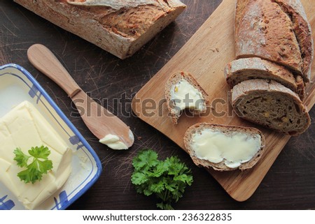 Bread on cutting board and slices of bread with butter