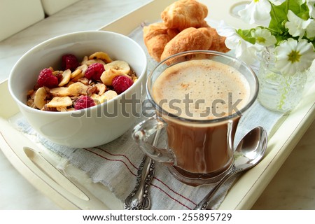 Tray with coffee, cereals with fruits and croissants for breakfast