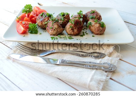 Meat balls with parsley and tomatoes on a plate