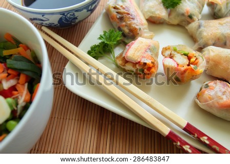 Spring rolls with vegetables, chicken and surimi sticks on a plate