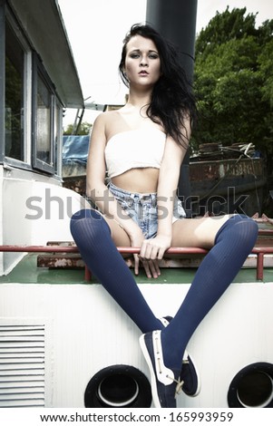 Woman posing for glamour and fashion photos outdoor on river boat.