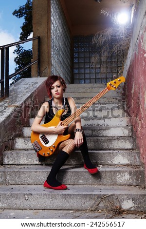 Bass guitar woman player posing on street city location for stylish musician portraits