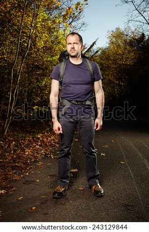 Man on track with bag enjoying nature by city