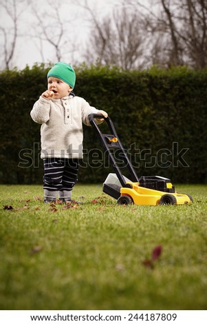 Little boy playing as lawn worker
