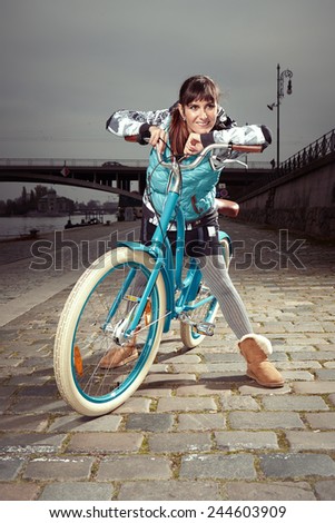 Nice young woman enjoying fancy stylish retro bicycle when riding on paved city river bank