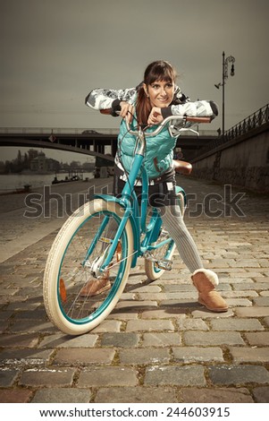 Woman enjoying stylish retro bicycle when riding on paved city river bank