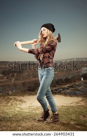Blonde nice young woman holding a giant hammer