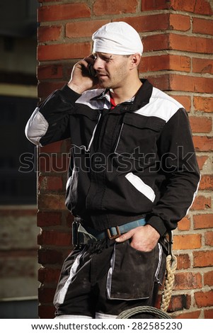 Chimney sweep man in work uniform doing business by phone