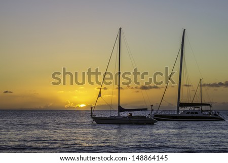 A summer Hawaiian ocean sunset  behind two sailboats