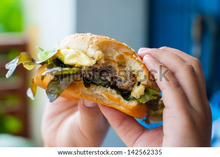 A fast food cheeseburger with a bite taken out of it