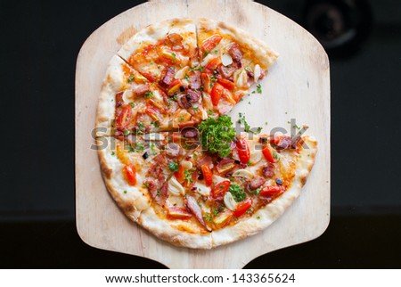 Pizza with bacon, garlic and dried chilli on wooden spatula