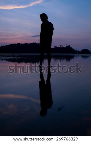 Man on the beach with reflection in water during sunset.Thailand