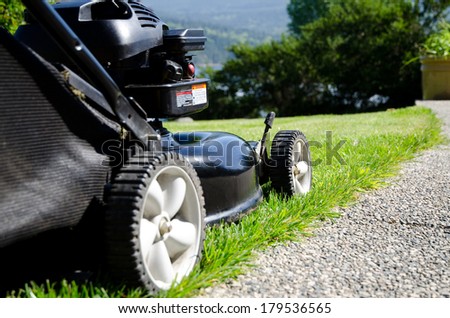 Black gas powered lawn mower close up cutting grass