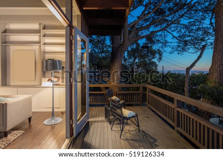 Wooden deck / balcony at night with open doors leading to living room.