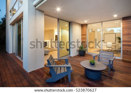 Wooden deck / balcony at night with open doors leading to living