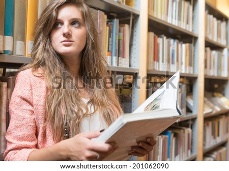 Portrait of a student in a library holding a book