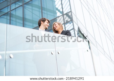 A young business couple standing and smiling in a modern buildings environment