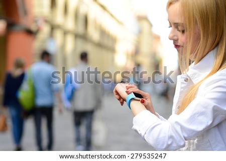 BOLOGNA, ITALY - MAY 17, 2015: One girl looks at the apple watch on her wrist in one of the city center street.