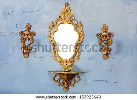 Golden vintage mirror with gold candlestick on wall