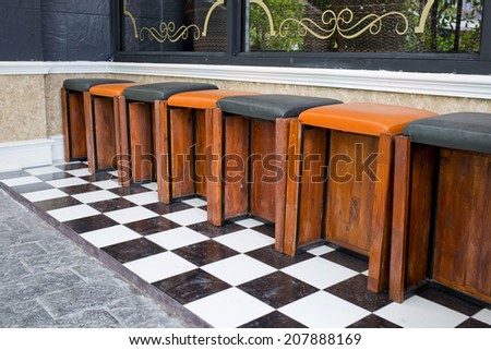 Classic wooden bar stools are lined up at an outdoor bar.