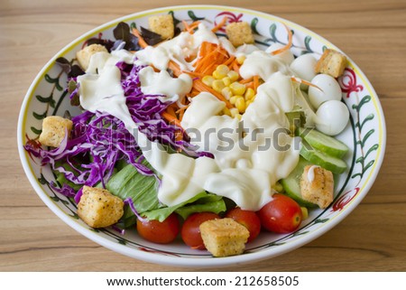 Fresh Green Organic Garden Salad in big bowl with salad cream on wooden background.