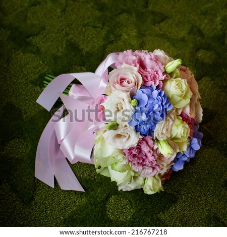Bouquet of blooming colorful flowers on a green carpet background.