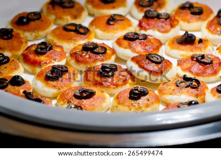 round meat pies with topping black olive sliced on buffet line