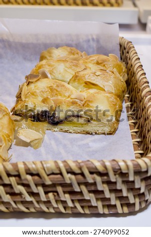 Close up of soft bread roll or bun with slice almond topping in basket at bakery shop