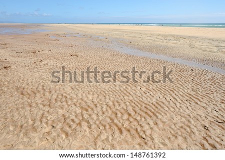 Fuerteventura, Canary Islands. A wet beach on a sunny day with the sea on the horizon, where the water has formed small puddles, pools, spots or pouches of water