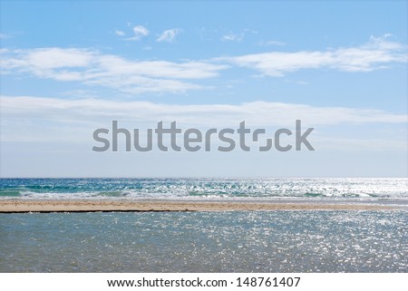 Fuerteventura, Canary Islands. A wet beach on a sunny day with the sea on the horizon, where the water has formed small puddles, pools, spots or pouches of water