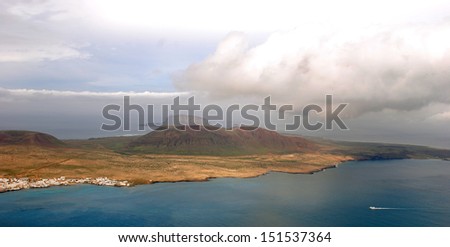Lanzarote, Canary Islands. A small island with a small town with white houses, in the side of Lanzarote, and a strait in between.