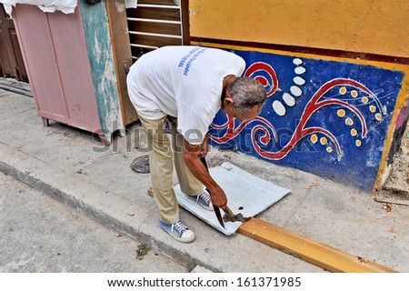 HAVANA, CUBA, OCTOBER 20, 2009. A man cutting sheet iron with a knife and a hammer, in Havana, Cuba, on October 20th, 2009.