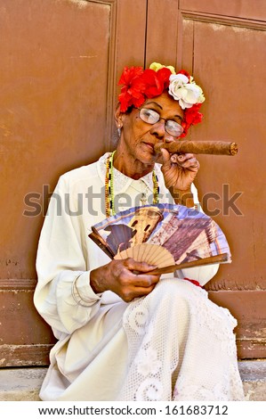 HAVANA, CUBA, MAY 6, 2009. An old woman sitting with a huge cigar in her mouth and roses in her head in Havana, Cuba, on May 7th, 2009.