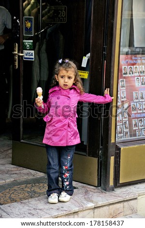 BITOLA, MACEDONIA, MAY 19, 2011. A small young girl in the age of four standing in a doorway with an ice cream on her hand, in Bitola, Macedonia, on May 19th, 2011.