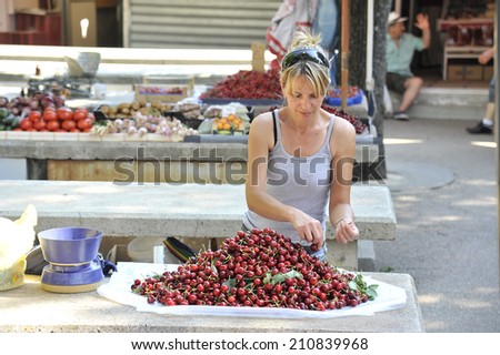 TROGIR, CROATIA, MAY 27, 2011. A blonde woman preparing cherries for selling in the marketplace in Trogir, Croatia, on May 27th, 2011.