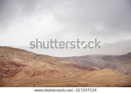 A cloudy day high in the Atlas Mountains, with a snowy mountain far in the horizon.