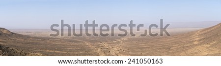 A panoramic view over the desert and a dried river in the wide open valley in the Anagan Pass in the Atlas Mountains of Morocco.