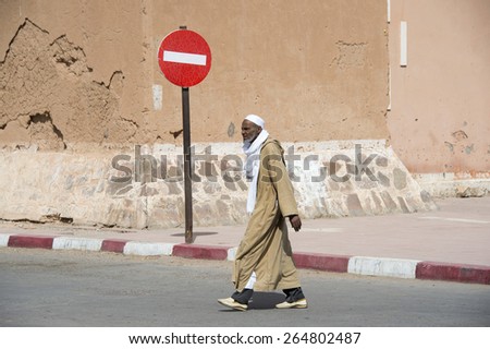 ZAGORA, MOROCCO, MARCH 8, 2014. A stylish old Moroccan man in a long brown gown crossing the street in Zagora, in Morocco, on March 8th, 2014