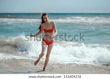 Girl running on the waves on the beach smiling and laughing