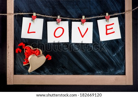 paper cards with letters LOVE attached with clothes pins on the lace on the chalkboard background