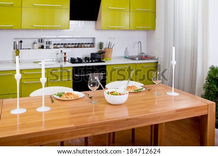 Salad on the dinner table with pasta and wine glasses on kitchen background