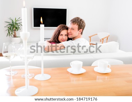 Young married couple sitting on the couch and watching tv at home, rare view