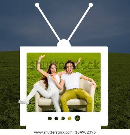 ?razy couple sitting on the couch in the green field looking through the television