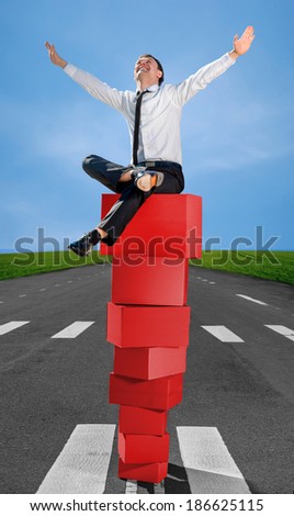 Successful and smiling business man on the top of pyramid made of red boxes on the road