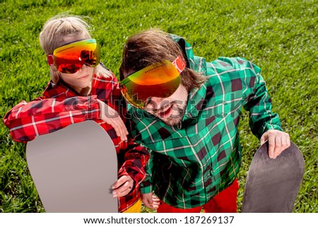 Couple in ski suit and sun glasses have a funny look to the camera on the grass background