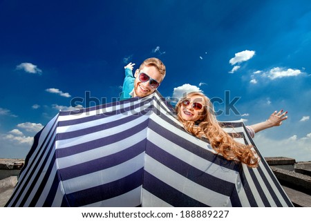 Emotional couple flying with umbrella and having fun on the blue sky background