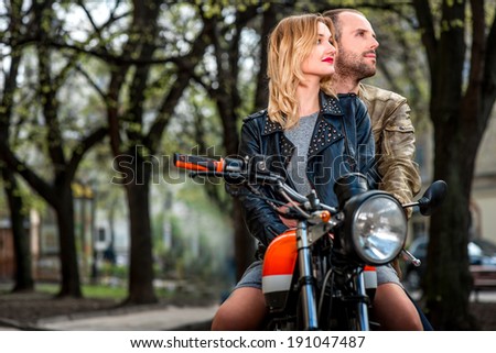 Couple sitting on the motorcycle in the city park