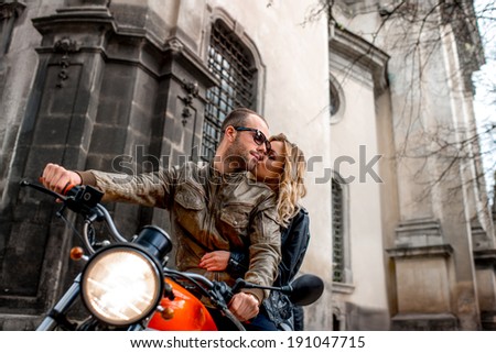 Young couple kissing and riding motorcycle in the old city